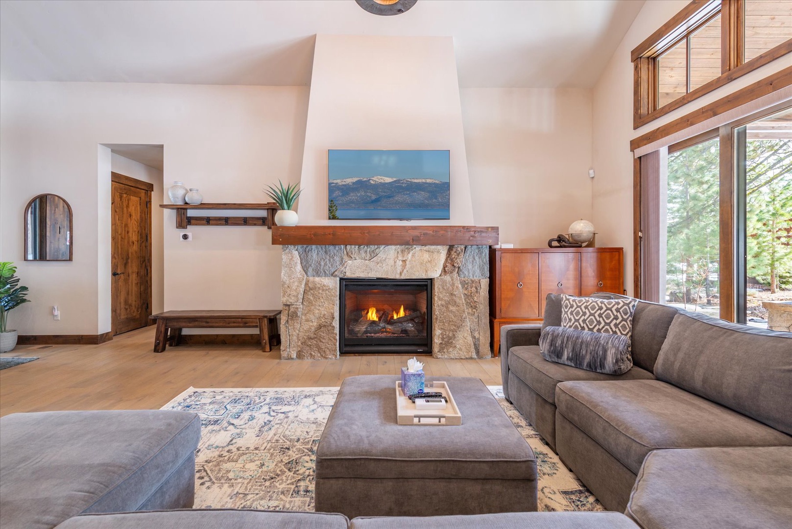 Sink into plush sofas beside your crackling fireplace, where natural light streams through floor-to-ceiling windows into this serene living space.