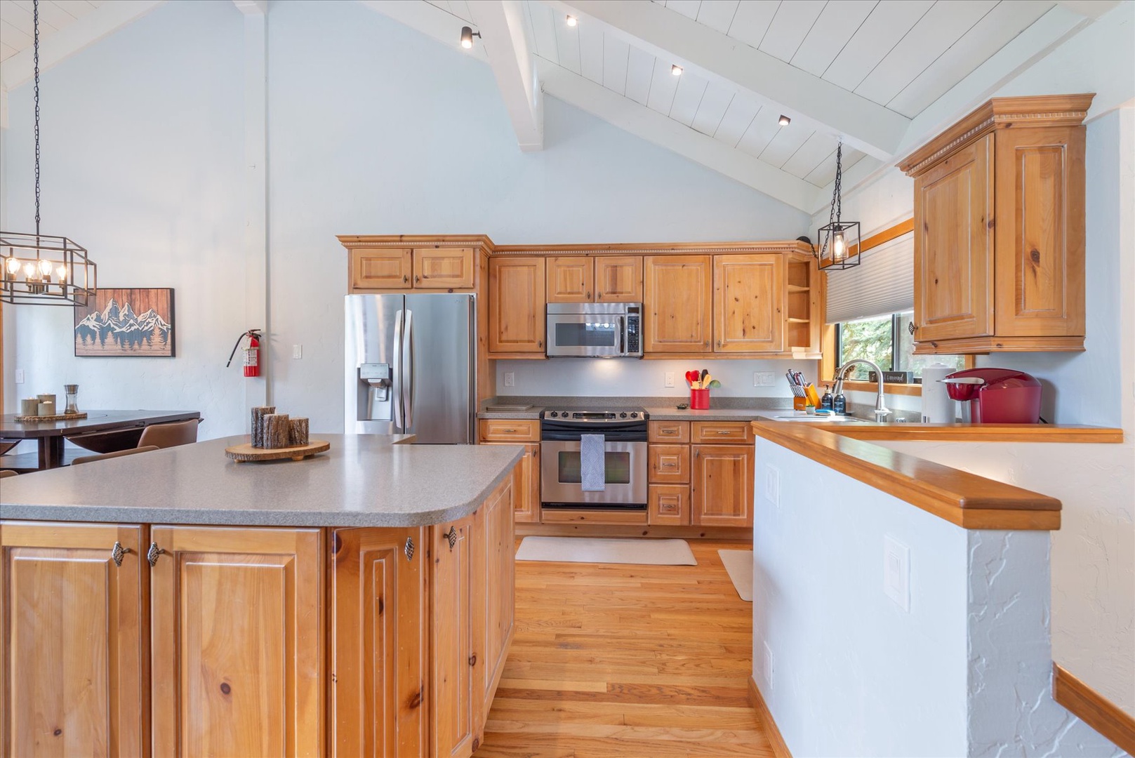Step into your fully equipped kitchen with vaulted ceilings, warm wood cabinetry, stainless appliances, and a spacious island perfect for gathering and creating memorable meals together.