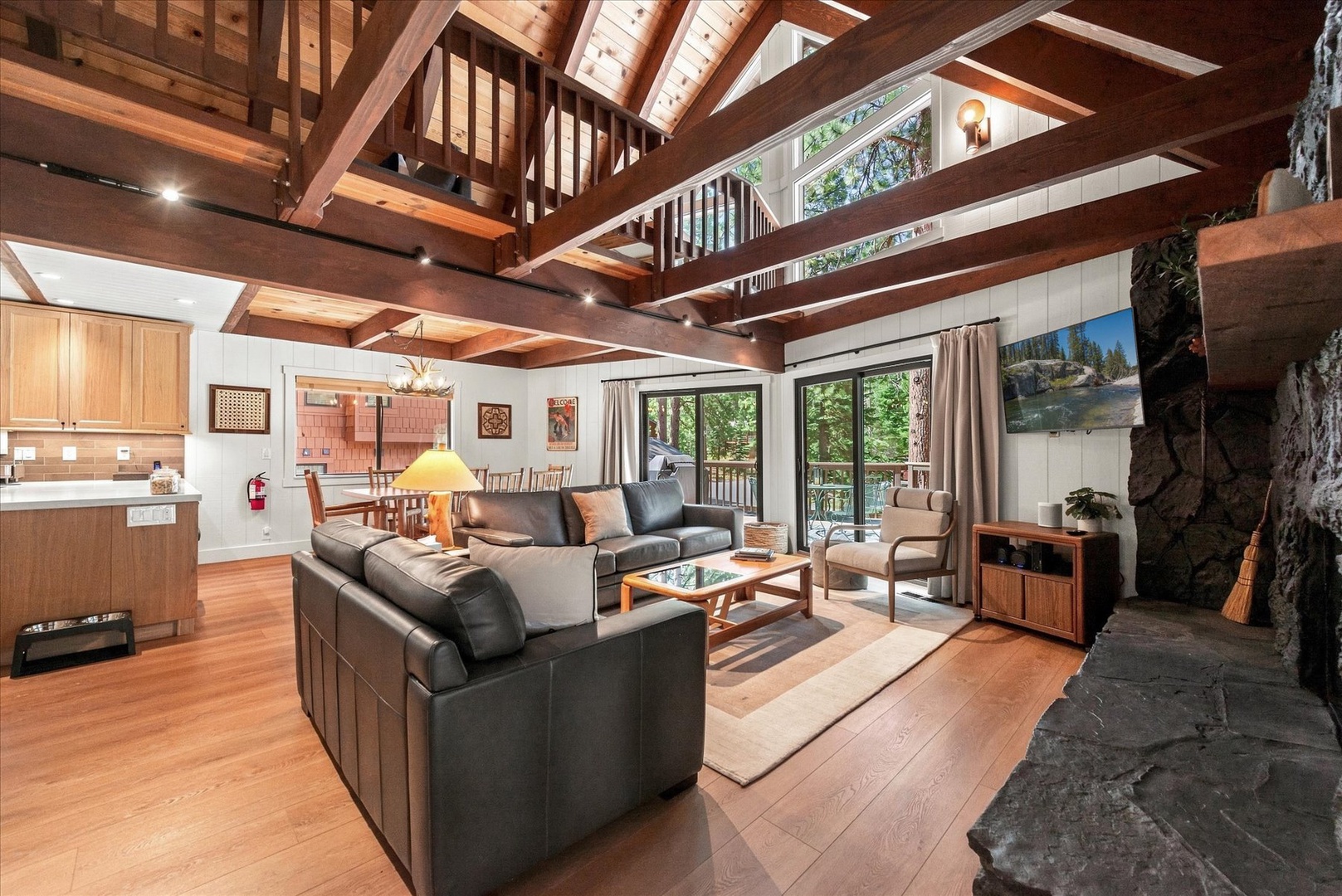 Step into your soaring retreat where warm wood beams frame an open space designed for togetherness. Sink into plush seating, gather around the fireplace, and let natural light flood through glass doors revealing your private deck.