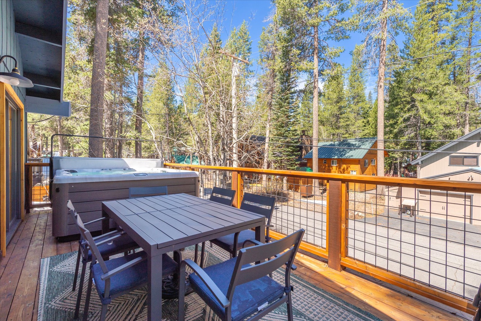 Unwind on your private deck with hot tub and dining table, surrounded by towering pines and peaceful forest views.