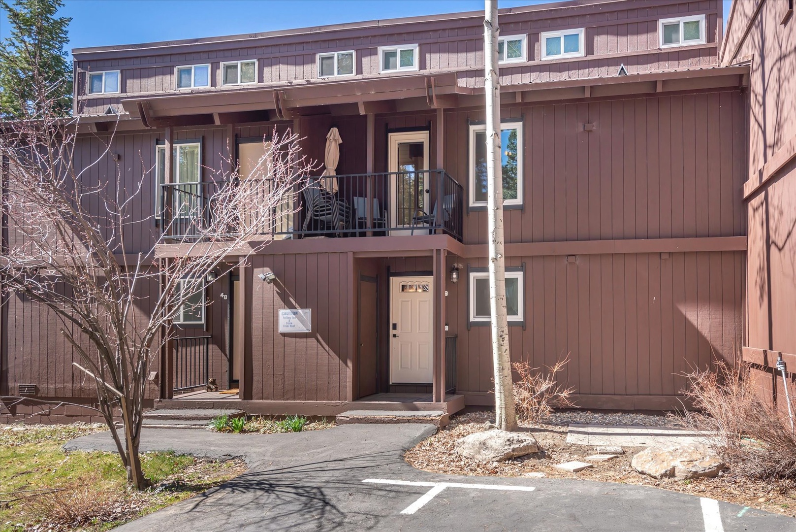 Mountain lodge-style building with wood exterior and welcoming entrance, featuring parking and natural landscaping.
