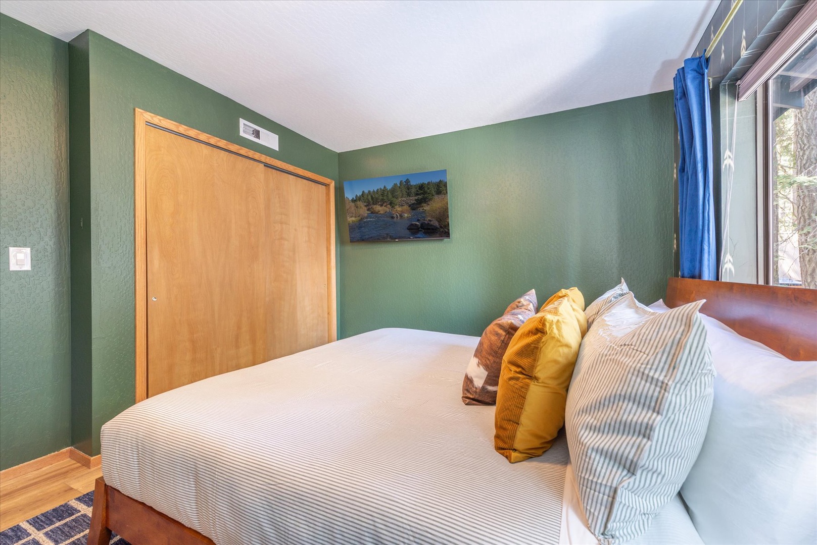 Sink into this cozy king bedroom's plush bedding and warm green walls, where natural light and thoughtful decor create your perfect retreat.