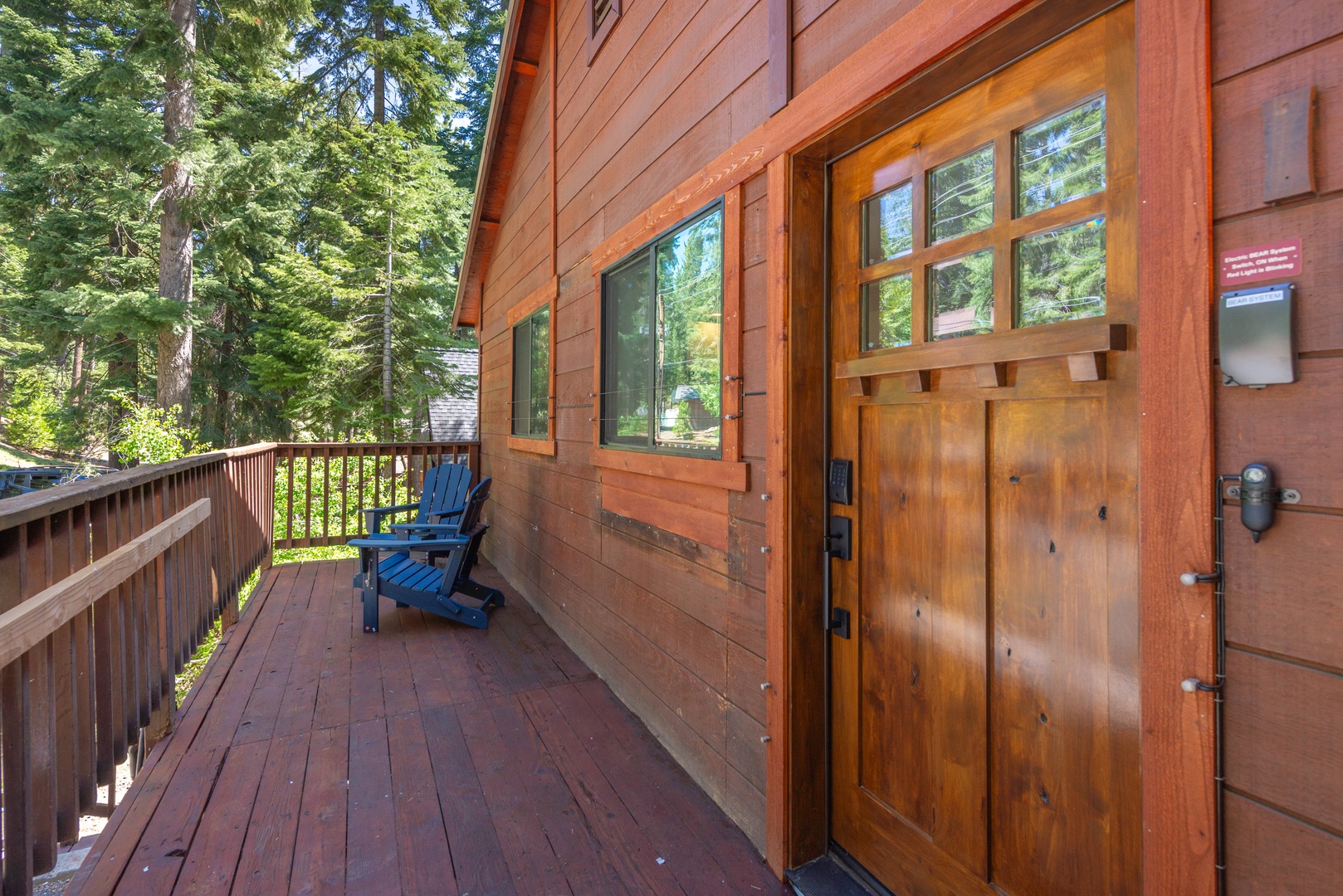 Nestled among towering pines, this inviting cabin entrance welcomes you to your tranquil forest retreat, where a quiet deck awaits your morning coffee and peaceful mountain moments.