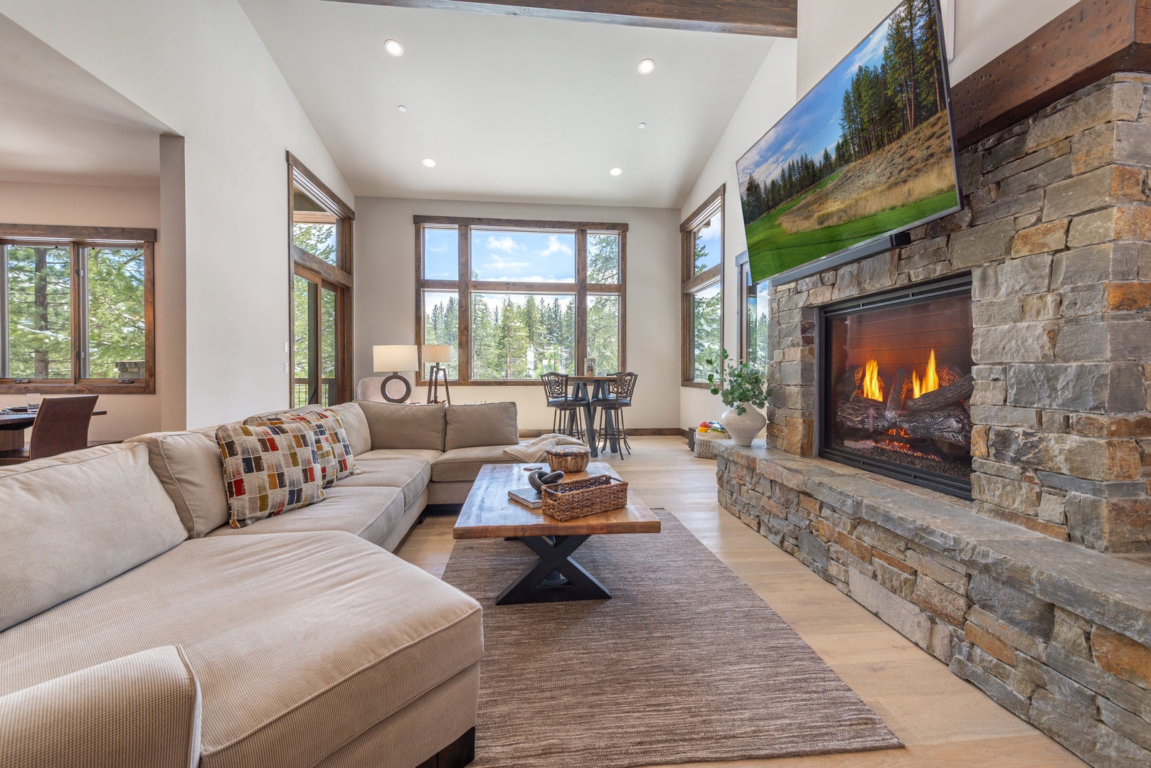 Cozy up in this stunning living room where rustic stone fireplace meets modern comfort, perfect for relaxing after your mountain adventures.