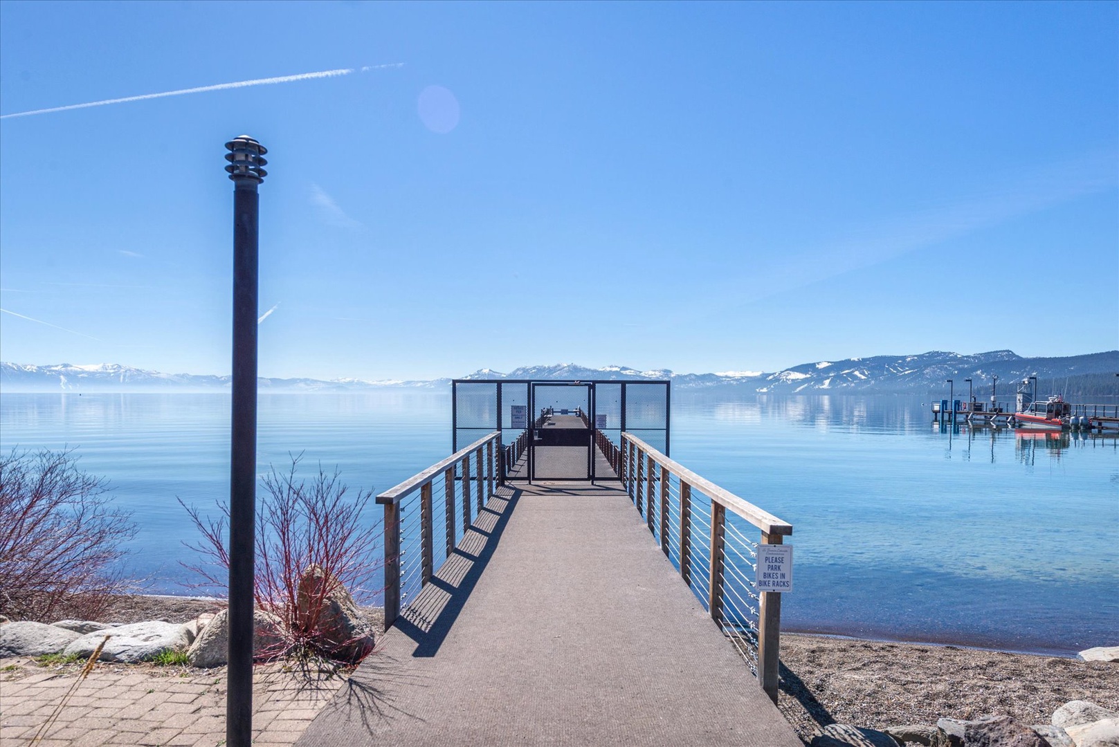 Scenic lake pier with mountain backdrop and crystal-clear waters in the surrounding area.