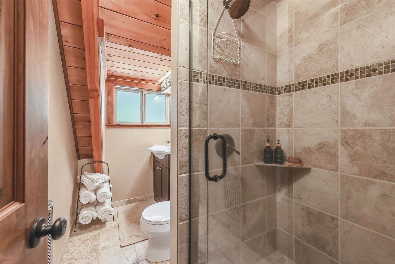 The upstairs bathroom has a beautiful walk-in shower, soft towels at the ready, and warm wood accents.