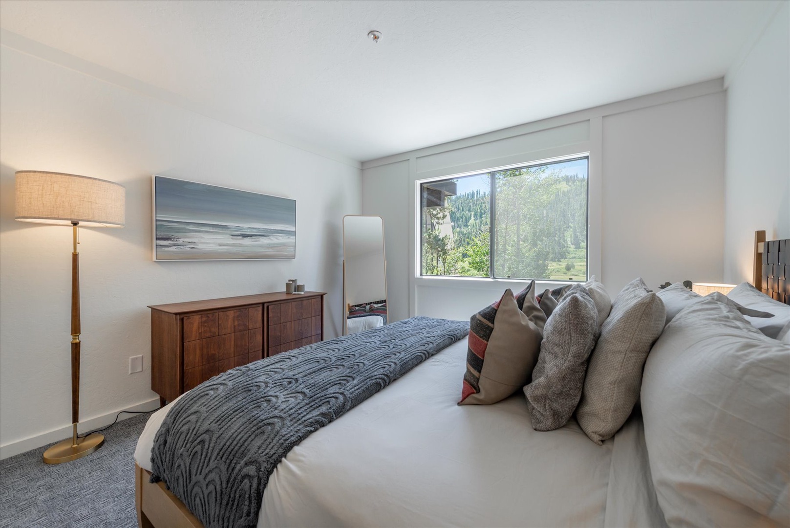 Wake up to stunning mountain and forest views from your serene bedroom retreat. Natural light fills the space, highlighting cozy textures and calming tones for your perfect getaway.