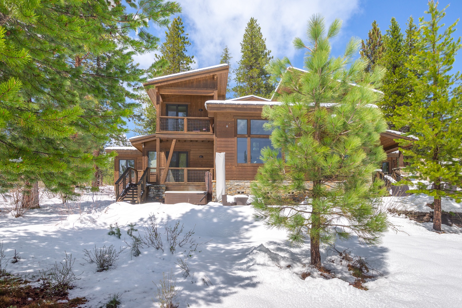 Modern mountain retreat nestled among snow-dusted pines under brilliant blue skies, offering alpine tranquility.