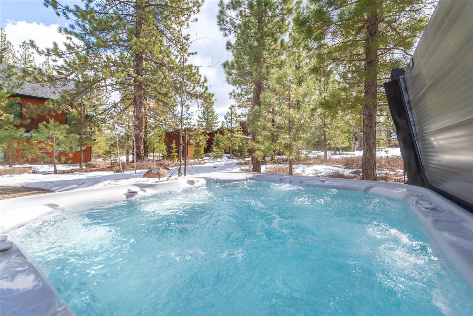 Soak in your private hot tub surrounded by towering pines and fresh mountain air, where bubbling warmth meets winter's serene beauty.