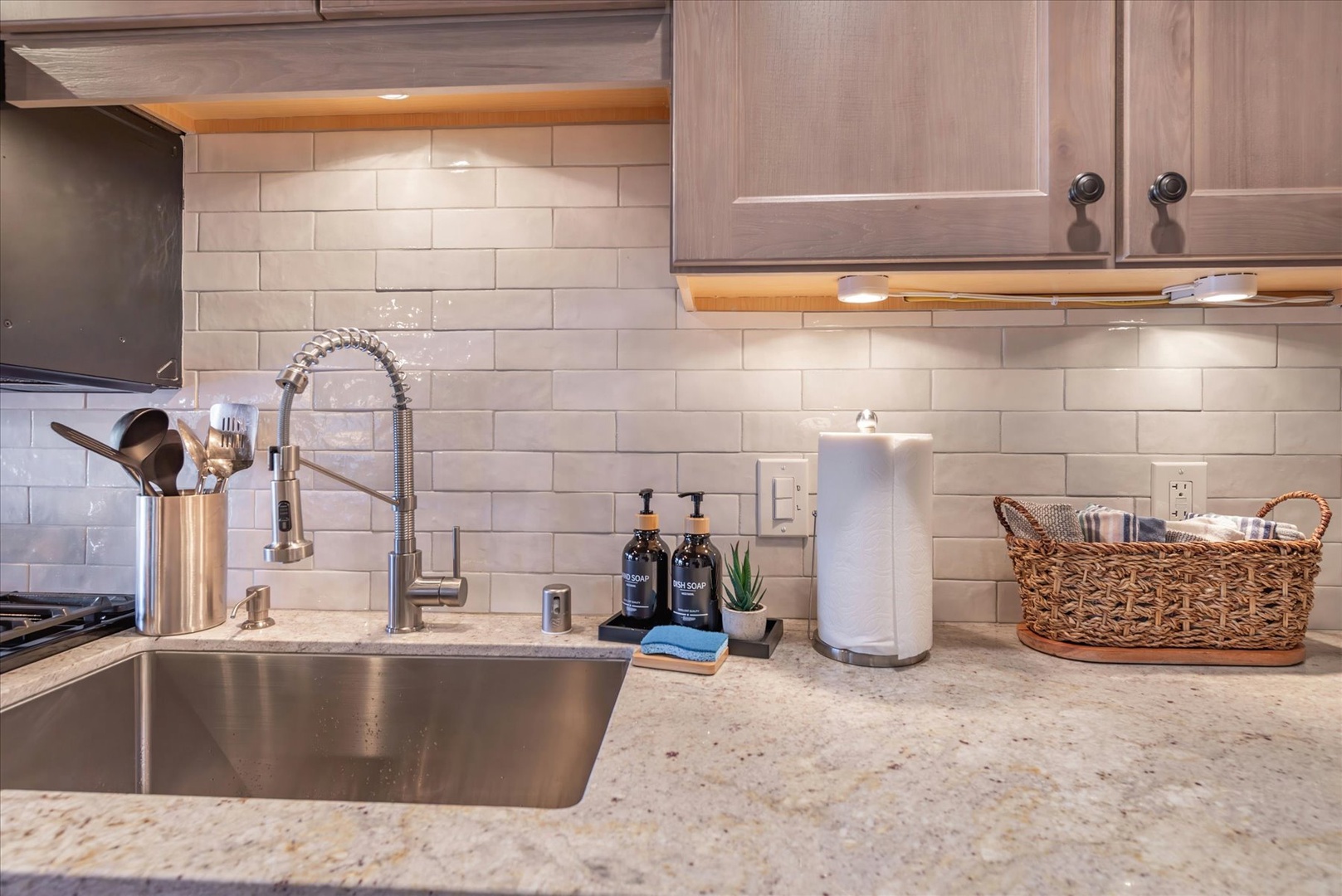 Your beautifully appointed kitchen features granite countertops, subway tile backsplash, and thoughtful touches like premium soap dispensers and a charming wicker basket.
