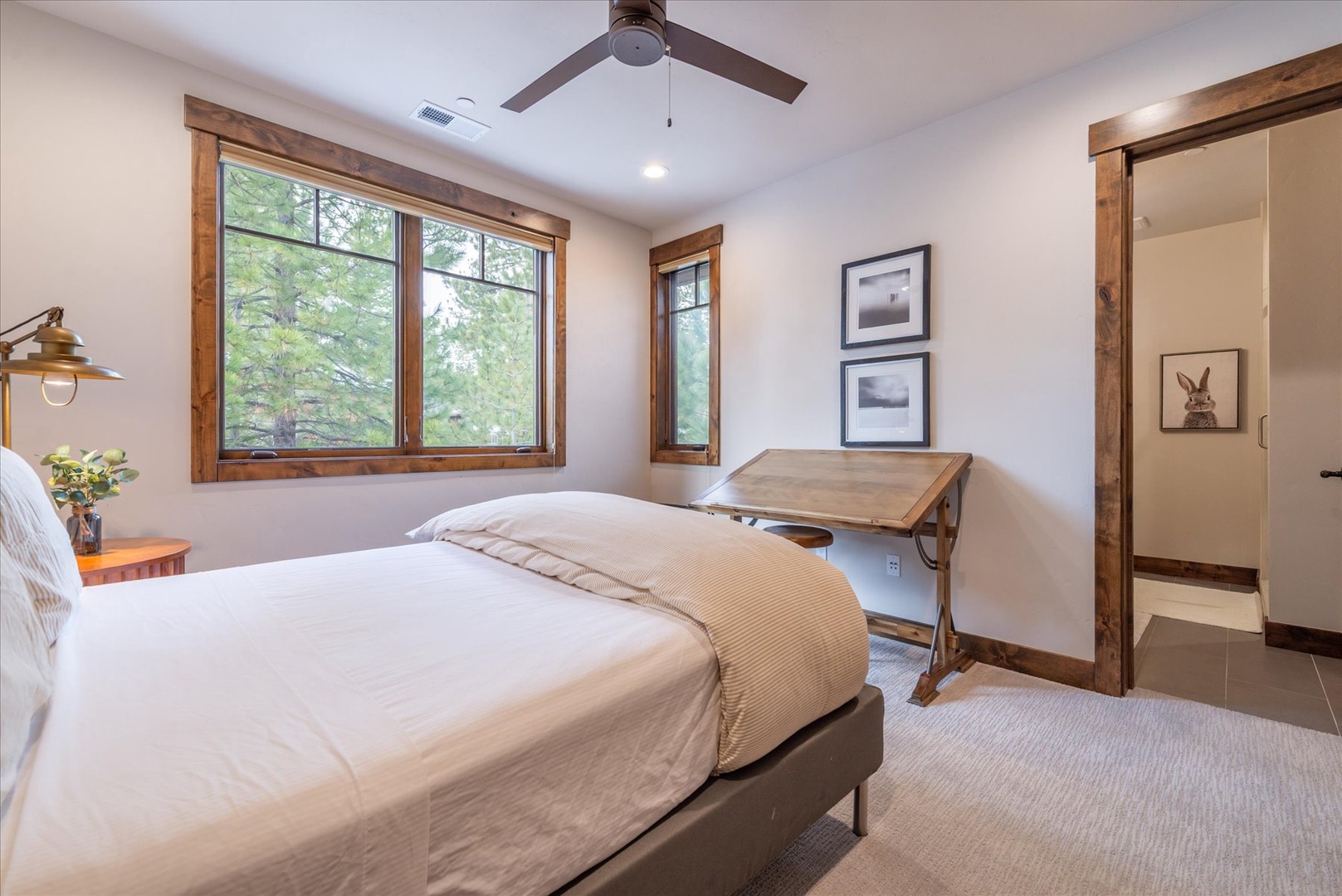 Unwind in this serene bedroom where rustic wood beams meet modern comfort, complete with a workspace for inspiration.
