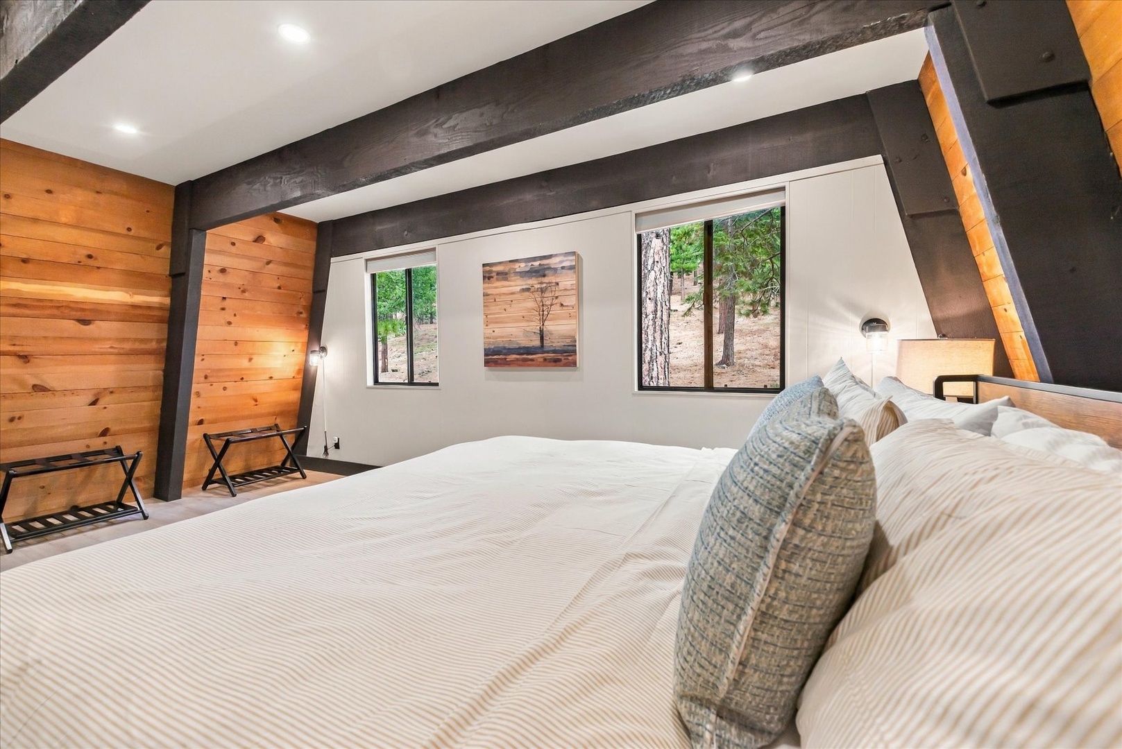 Drift off in this airy bedroom where rustic wood meets modern comfort. Natural light streams through large windows, and the crisp linens invite you to sink in after a day of adventure.