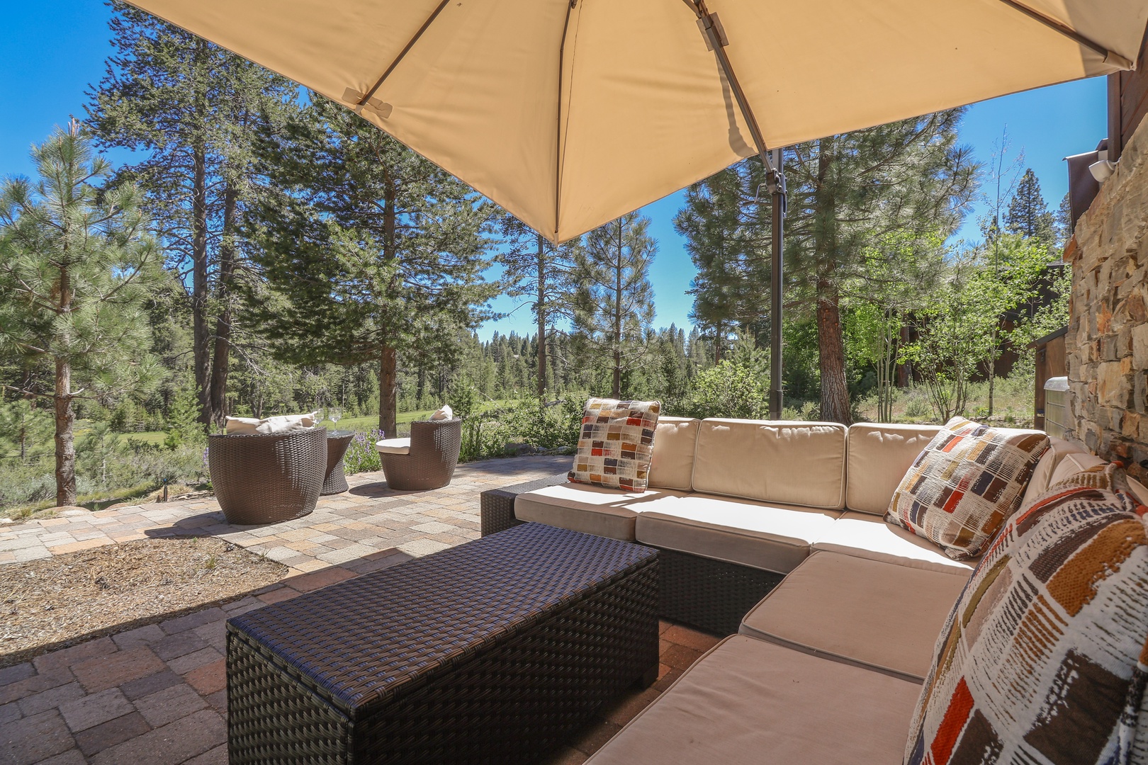 Sink into plush outdoor seating under the shade of your private patio umbrella, surrounded by towering pines and peaceful forest views that stretch endlessly beyond your retreat.
