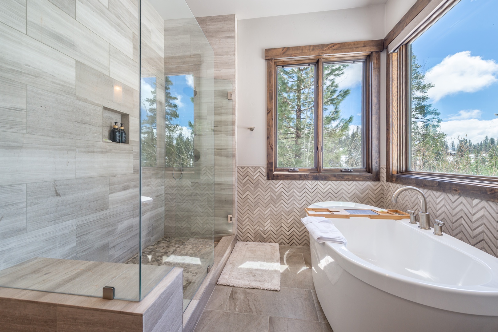 Indulge in your private spa-like retreat with a luxurious soaking tub and spacious walk-in shower overlooking serene forest views.
