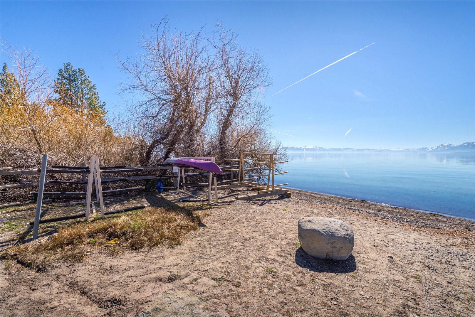 Lakeside recreation area with canoe storage overlooking pristine waters and the mountain backdrop.