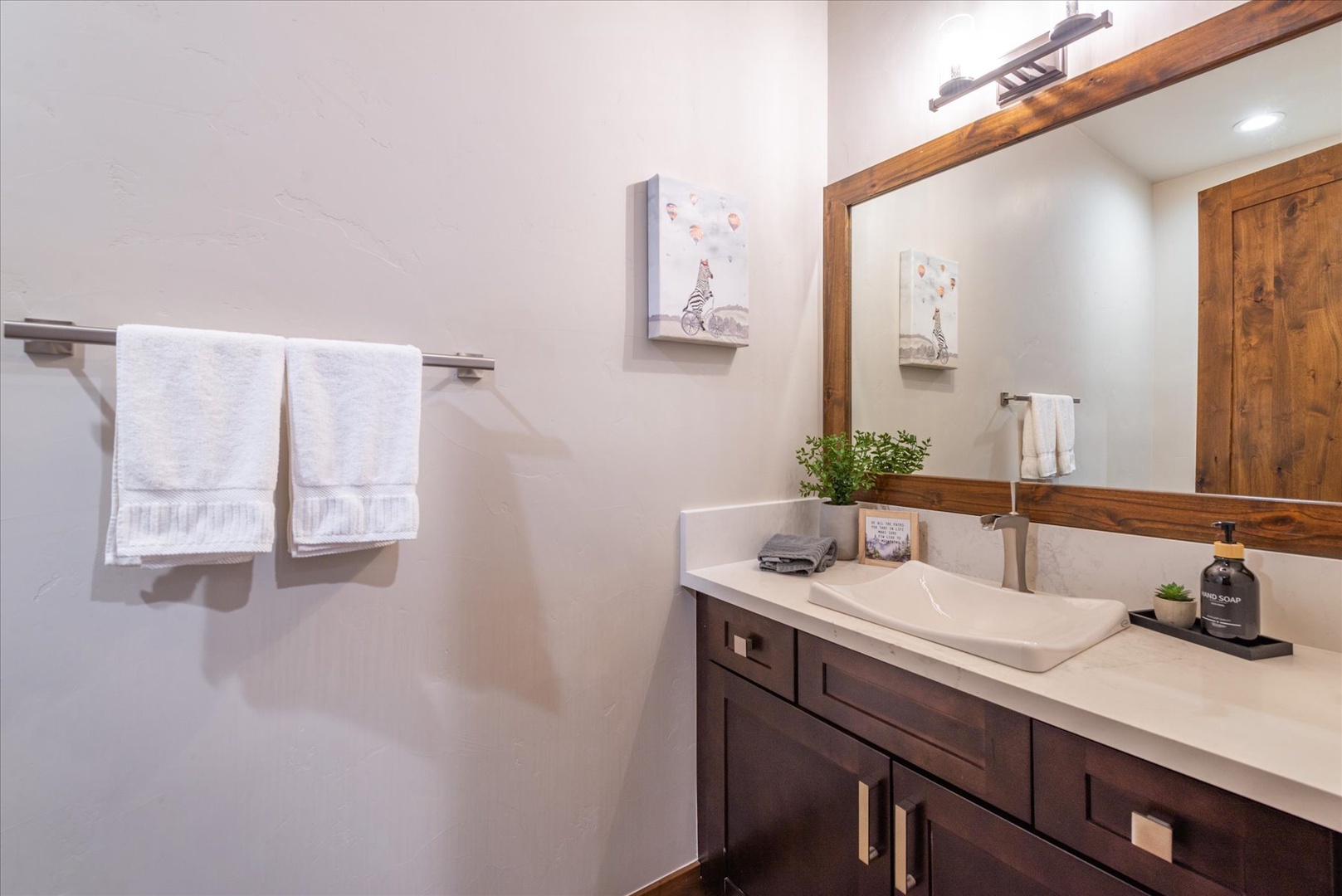 Refresh in your half bathroom off the living room, featuring modern fixtures and thoughtful touches like fresh towels and premium amenities.