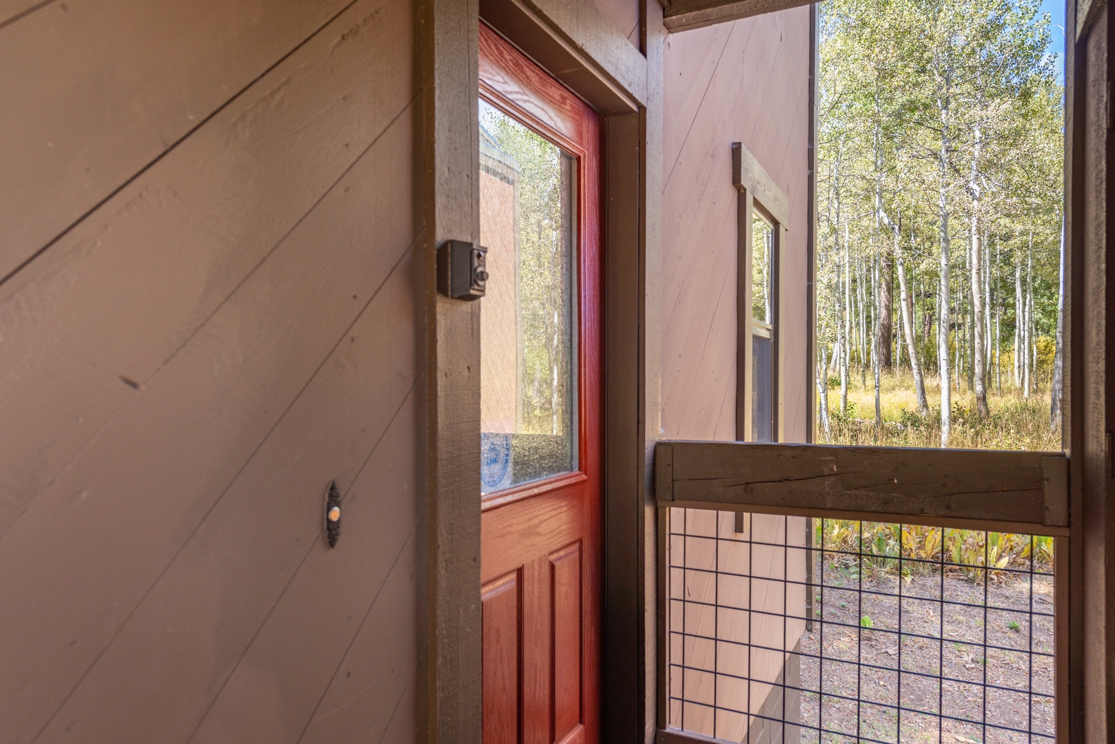 Step through the welcoming red door onto your private porch overlooking a peaceful grove of aspens, where golden leaves flutter in the breeze.