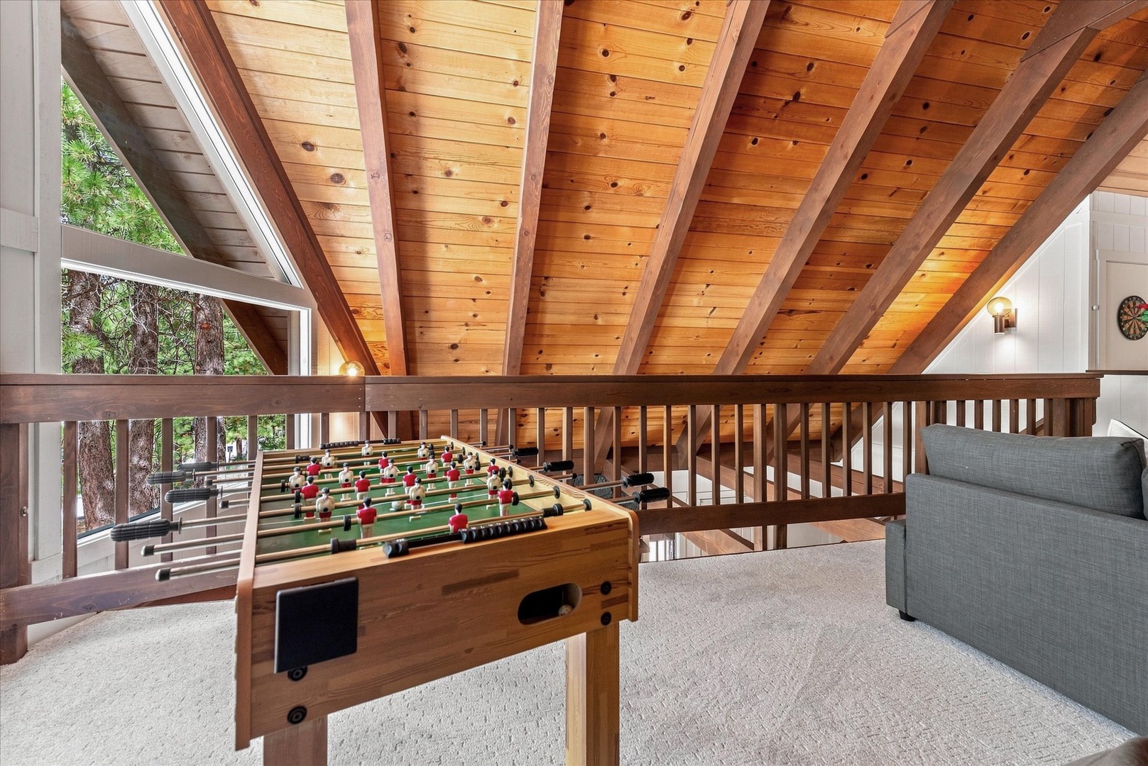 Challenge your friends to a game of foosball in this inviting loft space, where warm wood beams and forest views create the perfect mountain retreat for fun and relaxation.