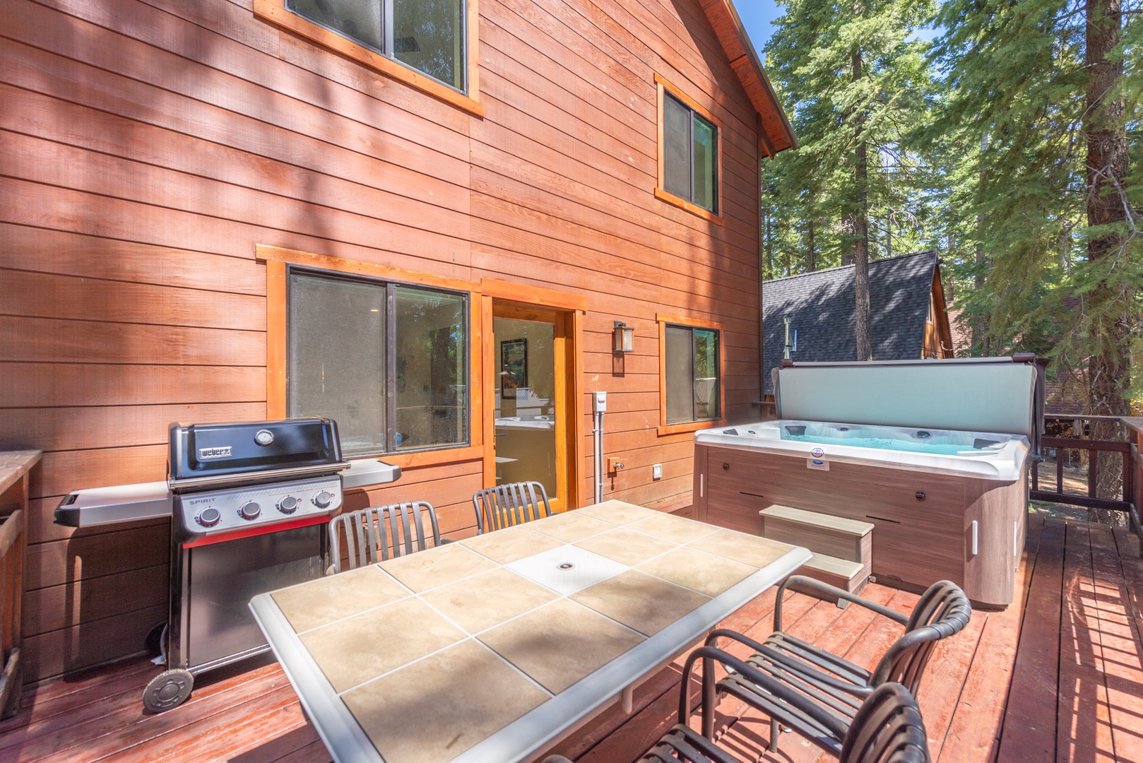 Your private outdoor retreat features a spacious deck with a bubbling hot tub, BBQ grill, and dining table—perfect for outdoor dining.