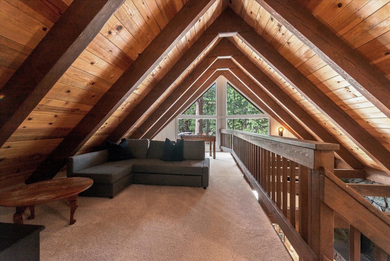 Curl up in your cozy loft retreat where soaring wood beams frame a peaceful garden view—a perfect hideaway for reading, relaxing, or simply soaking in the cabin charm.
