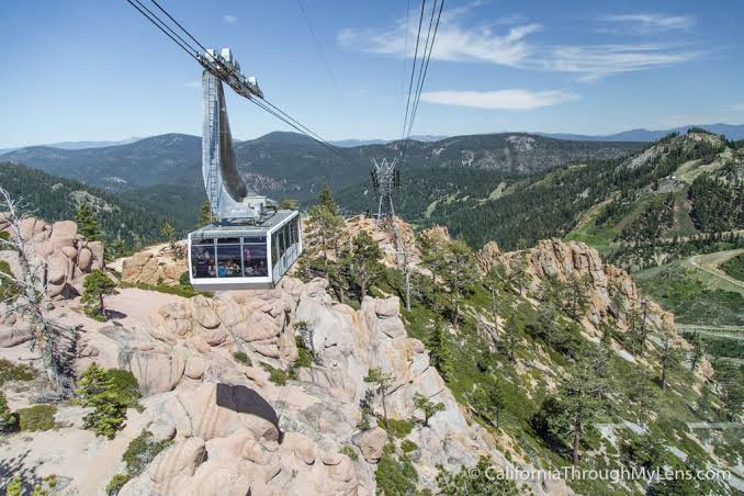 A cable car glides over rugged mountain peaks and forested slopes, part of the scenic area surrounding the property.