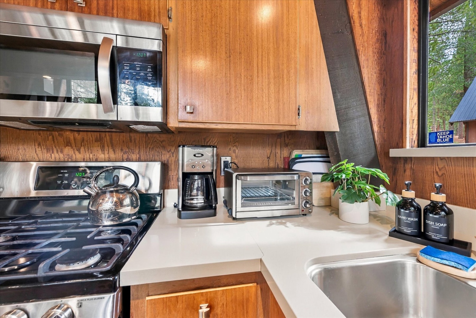 Your fully equipped kitchen includes a gas stove, microwave, toaster oven, and coffee maker, surrounded by warm wood cabinetry. Everything you need awaits for preparing simple breakfasts or full meals.