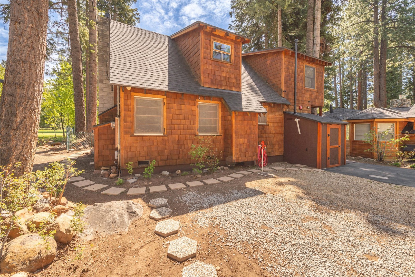 Charming wood-shingled cabin nestled among towering pines with private driveway and wooded setting for peaceful mountain retreat.