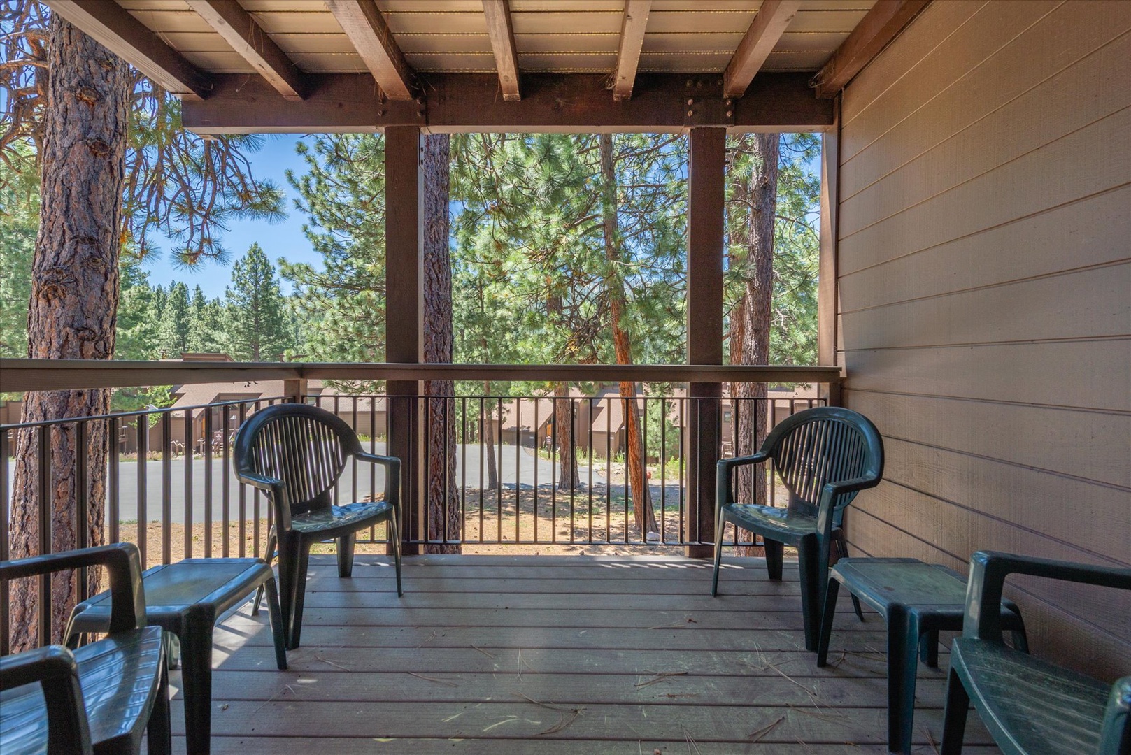 Your private covered balcony framed by towering pines invites you to unwind with morning coffee or evening relaxation, surrounded by peaceful forest views.