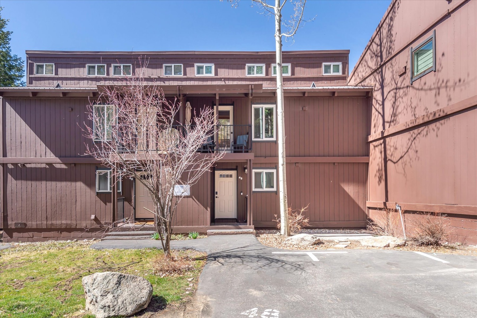 Wood-sided townhouse building with multiple levels and balconies in a peaceful residential complex.