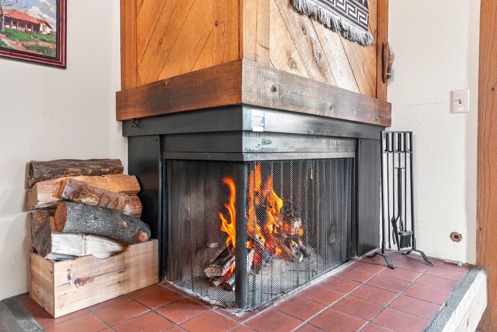 Gather around your rustic corner fireplace, where crackling flames and stacked firewood create a cozy mountain retreat ambiance after a day of adventure.