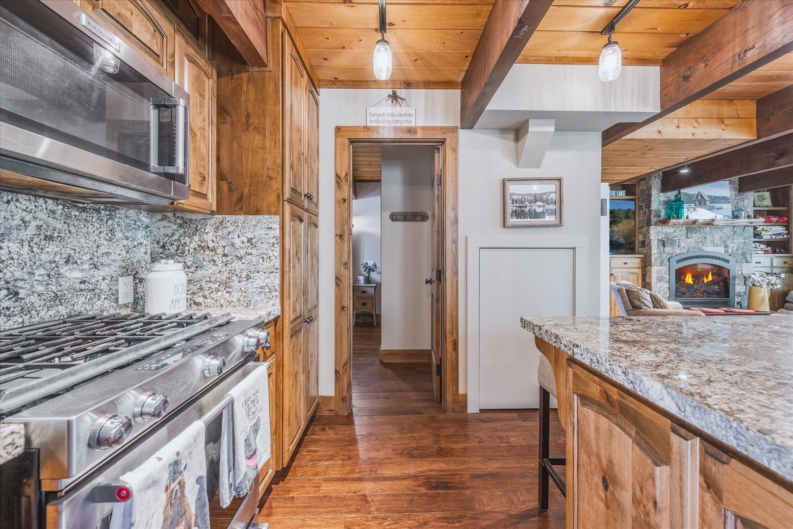 Granite counters and stainless steel appliances meet rustic charm, while a cozy fireplace glows just beyond, making every meal feel like home.