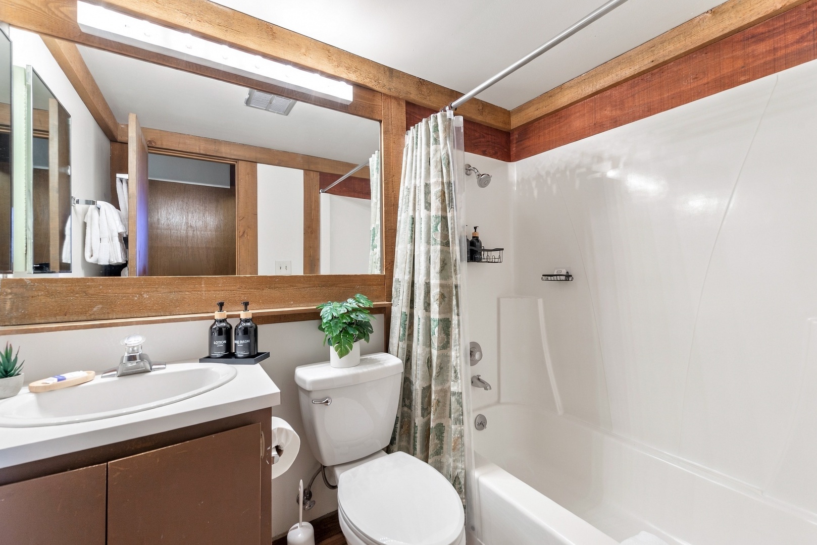 Step into your private bathroom featuring warm wood accents, a full tub-shower combo, and thoughtful touches like quality toiletries. Fresh, clean, and ready for your stay.