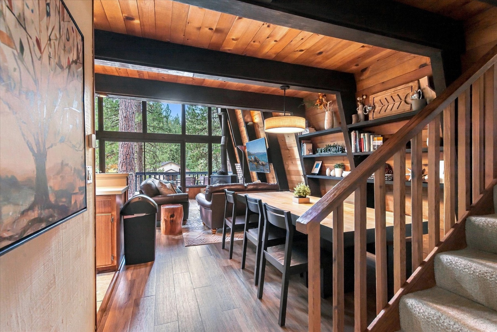 Warm wood tones and soaring ceilings define this mountain retreat. The open-concept living and dining area flows seamlessly, flooded with natural light from expansive windows framing the forest.
