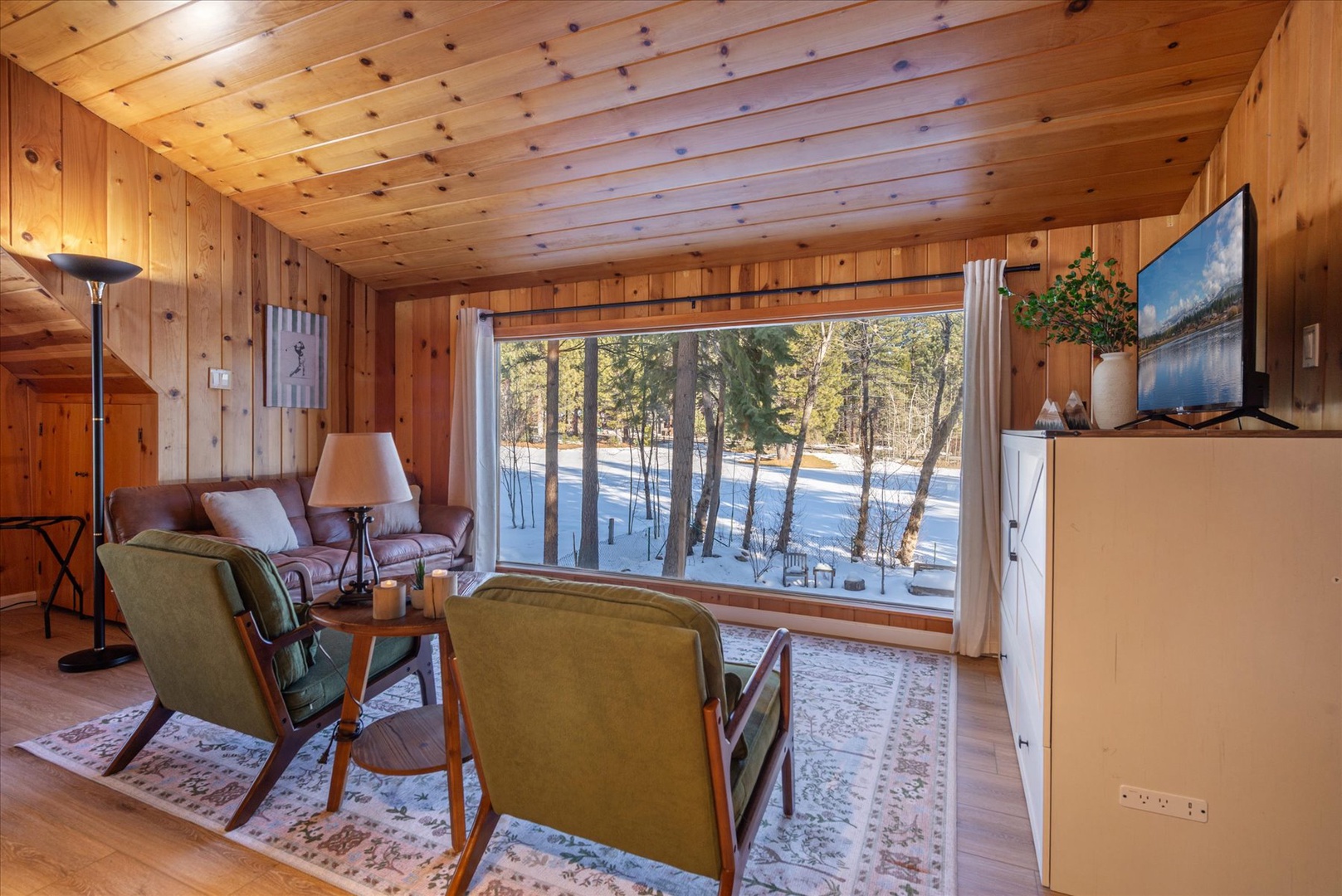 Enjoy your secondary living space in the master bedroom, where you can unwind with stunning winter forest views through large windows.