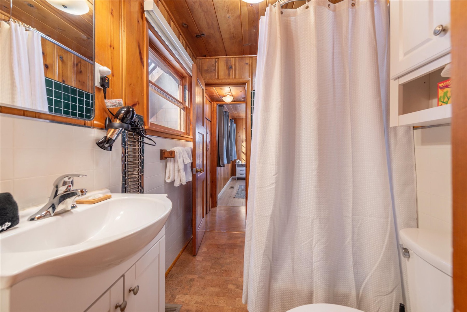 Step into your cozy bathroom with warm wood accents and all the essentials you need for a refreshing stay.