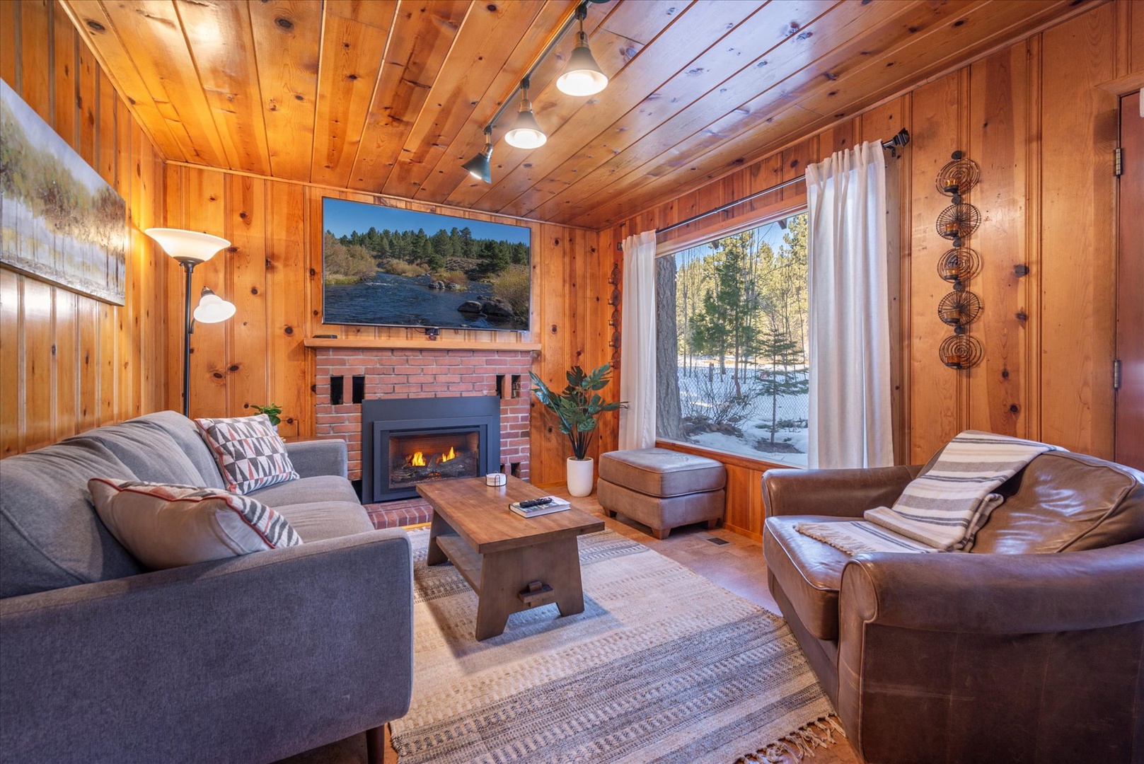 You'll love this warm and inviting living room framed by the large window showing forest views.