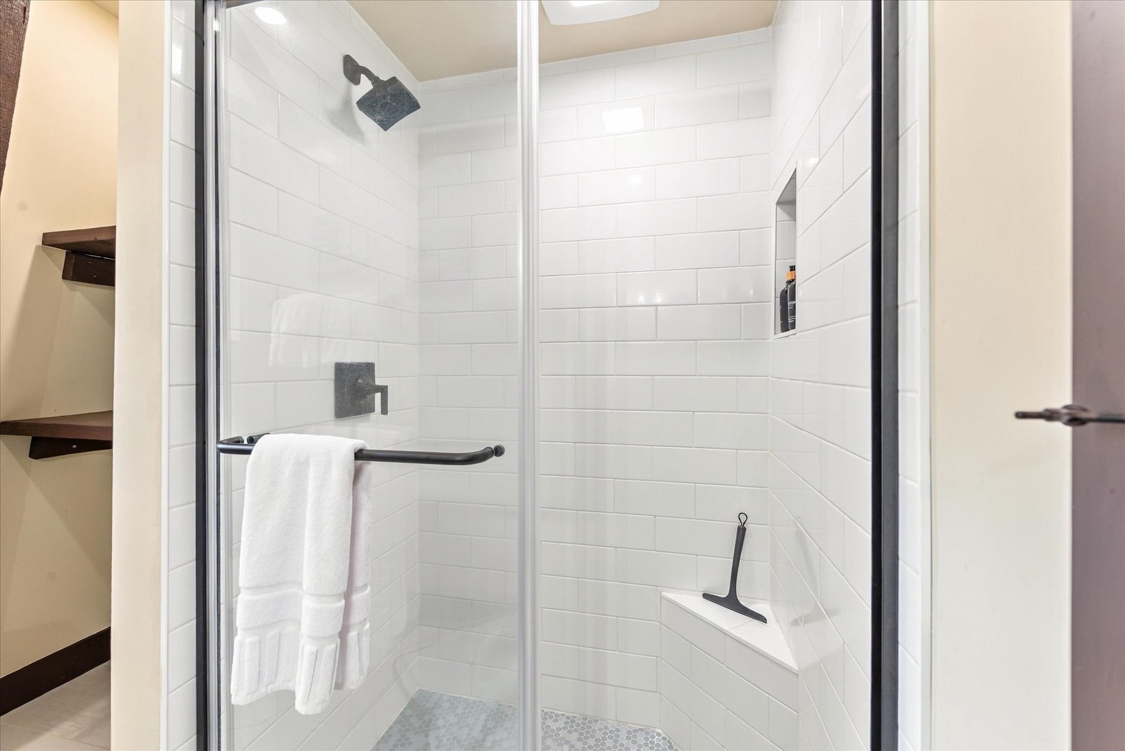 Step into your spacious walk-in shower with clean white subway tile, modern fixtures, and thoughtful touches like a built-in bench and niche for your essentials. Fluffy towels await.