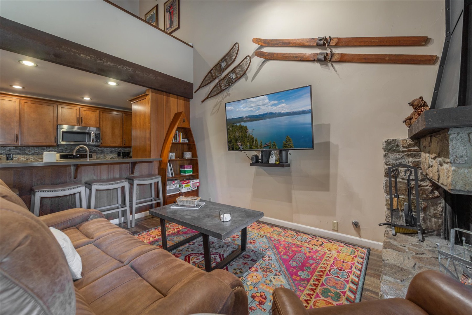 Unwind in your cozy living space featuring rustic charm, a stone fireplace, and vintage ski decor that captures mountain spirit perfectly.