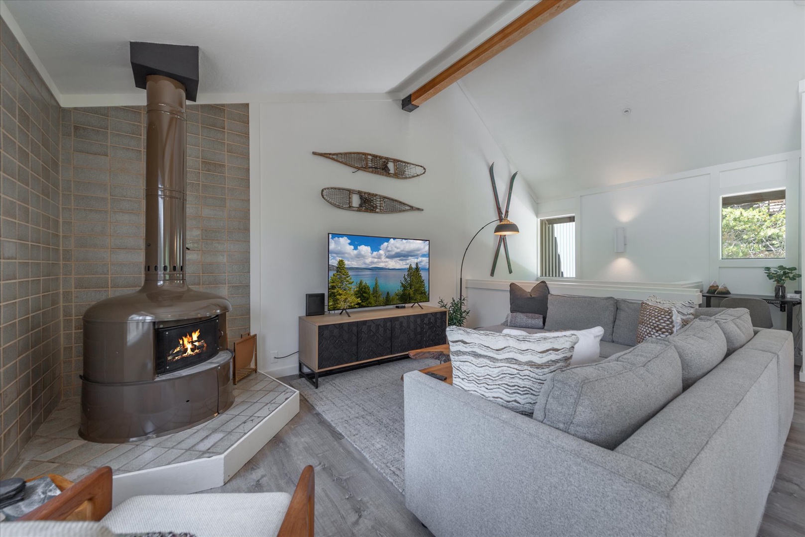 Curl up on the plush sofa and let the fireplace warm your evening while you unwind with a movie in this bright, inviting living space.