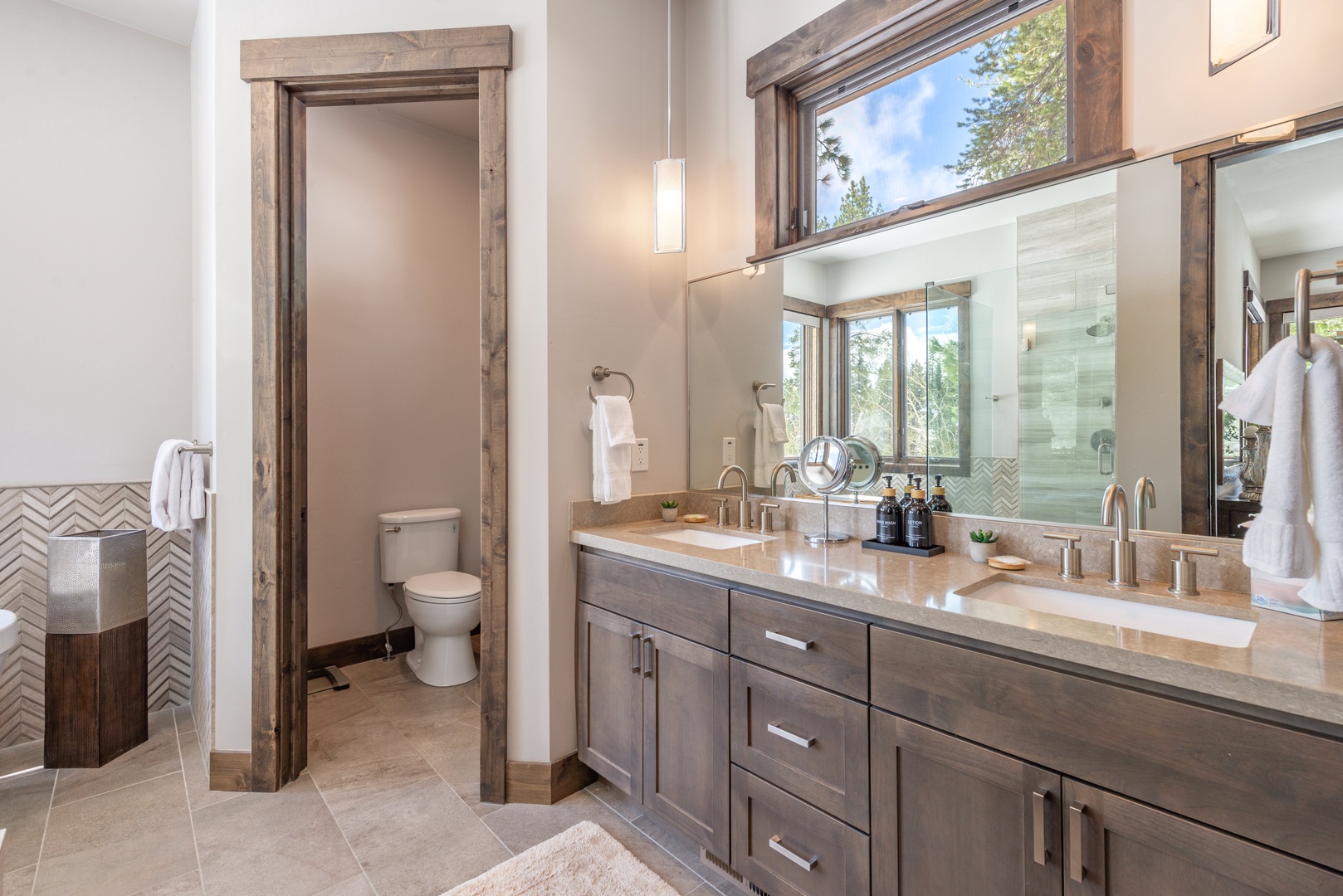Unwind in your luxurious bathroom with dual vanities, rustic wood accents, and natural light creating the perfect morning routine space.