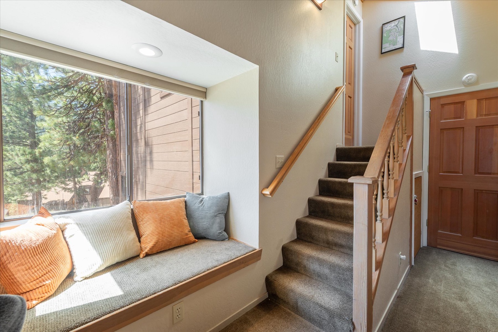 Settle into your cozy window nook with plush pillows and enjoy tree-lined views. Warm wood accents and natural light create a peaceful spot to unwind after exploring the surrounding forest.