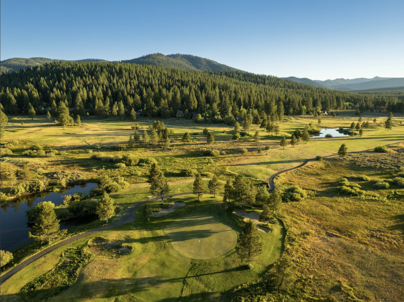 Aerial view of the Northstar golf course surrounded by lush forests and mountain scenery.