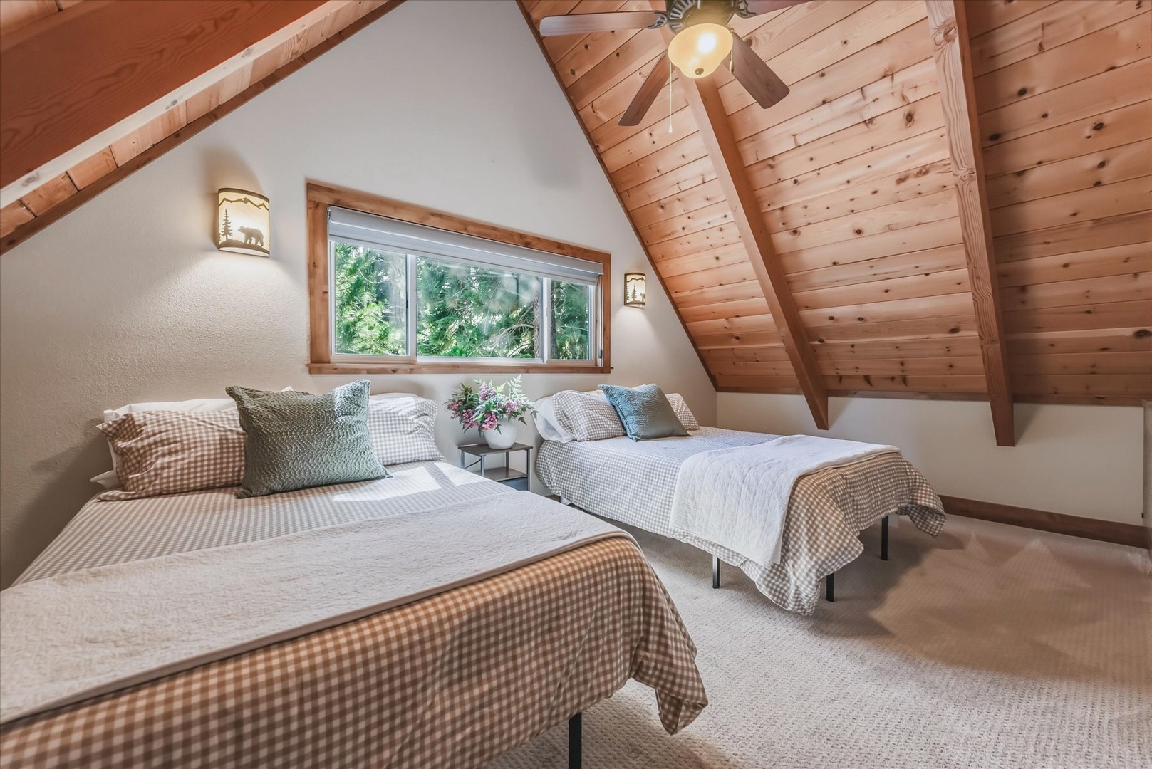 Wake up beneath vaulted pine ceilings and let natural light pour in through the loft window. These two queen beds offer a cozy retreat with rustic charm and a peaceful view of the surrounding trees.