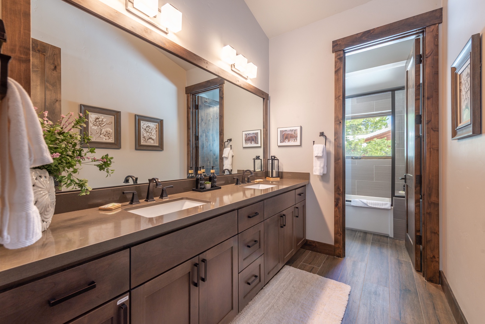 Pamper yourself in this beautifully appointed bathroom featuring warm wood accents, elegant dual vanities, and premium fixtures designed for your ultimate comfort.