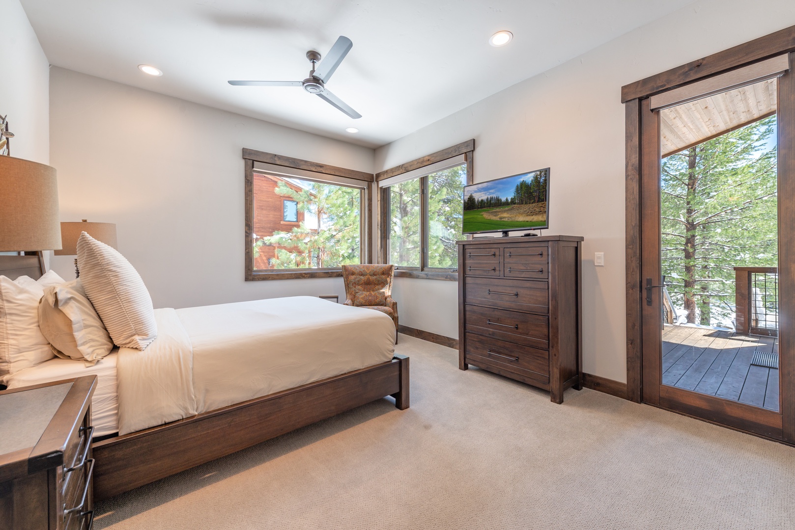 Wake up in your serene bedroom with forest views through large windows, a private balcony, and rustic wood furnishings creating your peaceful retreat.