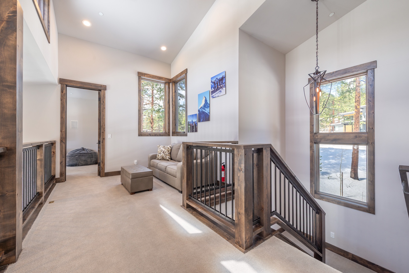 Unwind in this bright loft space with cozy seating and mountain artwork, where natural light streams through large windows.