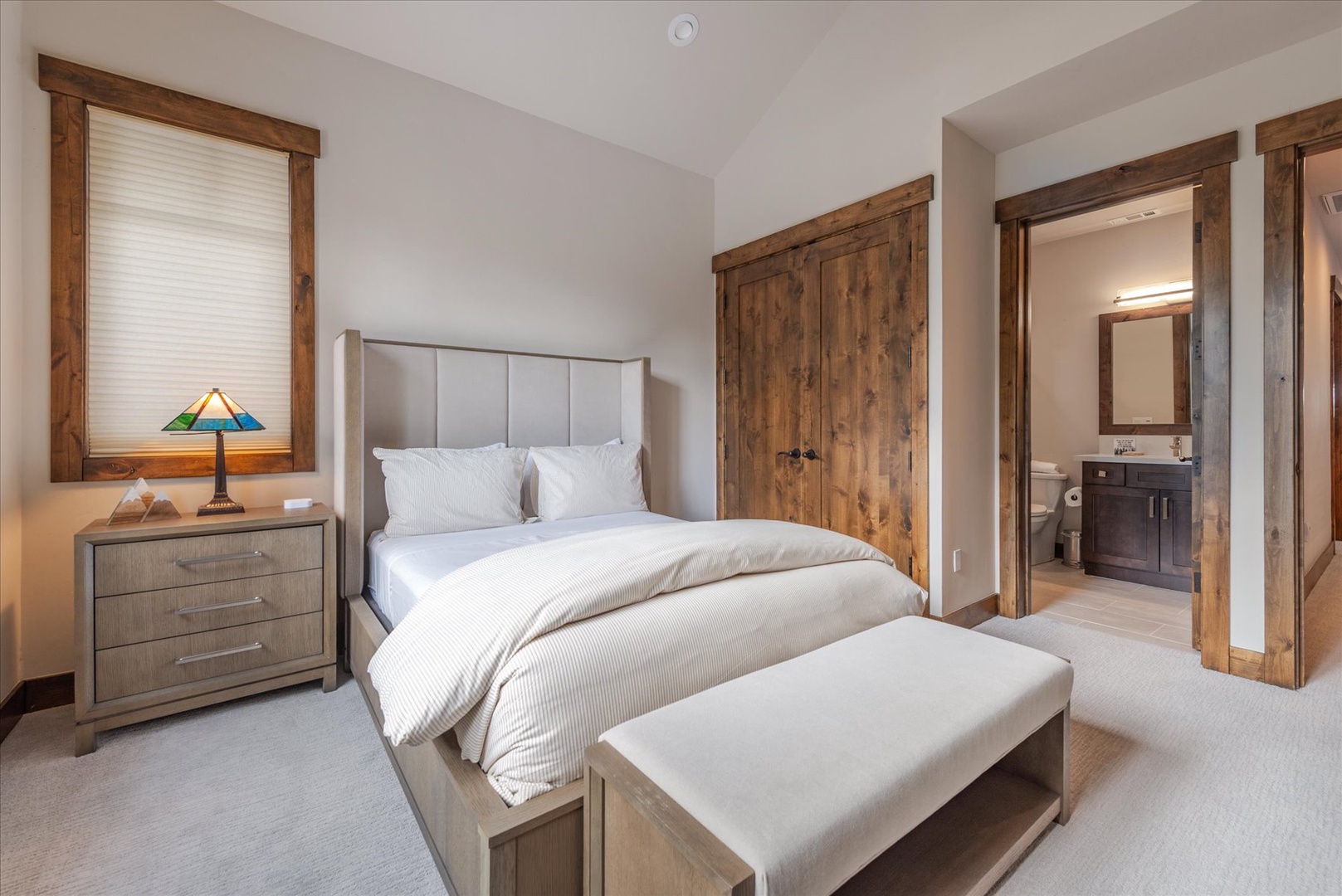 Sink into this serene bedroom where rustic wood meets modern comfort. Crisp linens and soft lighting create your perfect retreat.