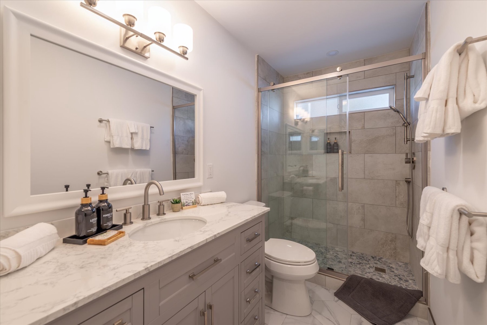 Another beautifully appointed bathroom upstairs with marble counters, a spacious glass shower, and plush towels waiting for your arrival.