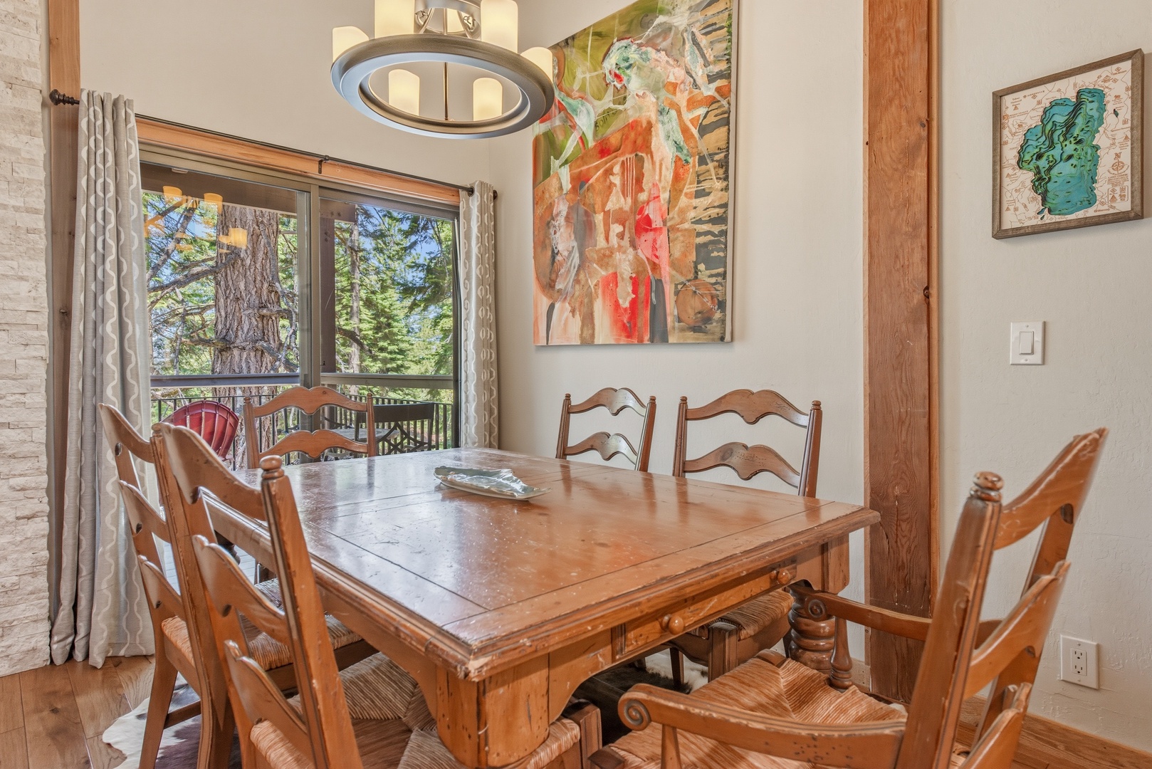 Gather around this rustic dining table for memorable meals, with colorful artwork adorning the walls and serene forest views framing your dining experience through the window.