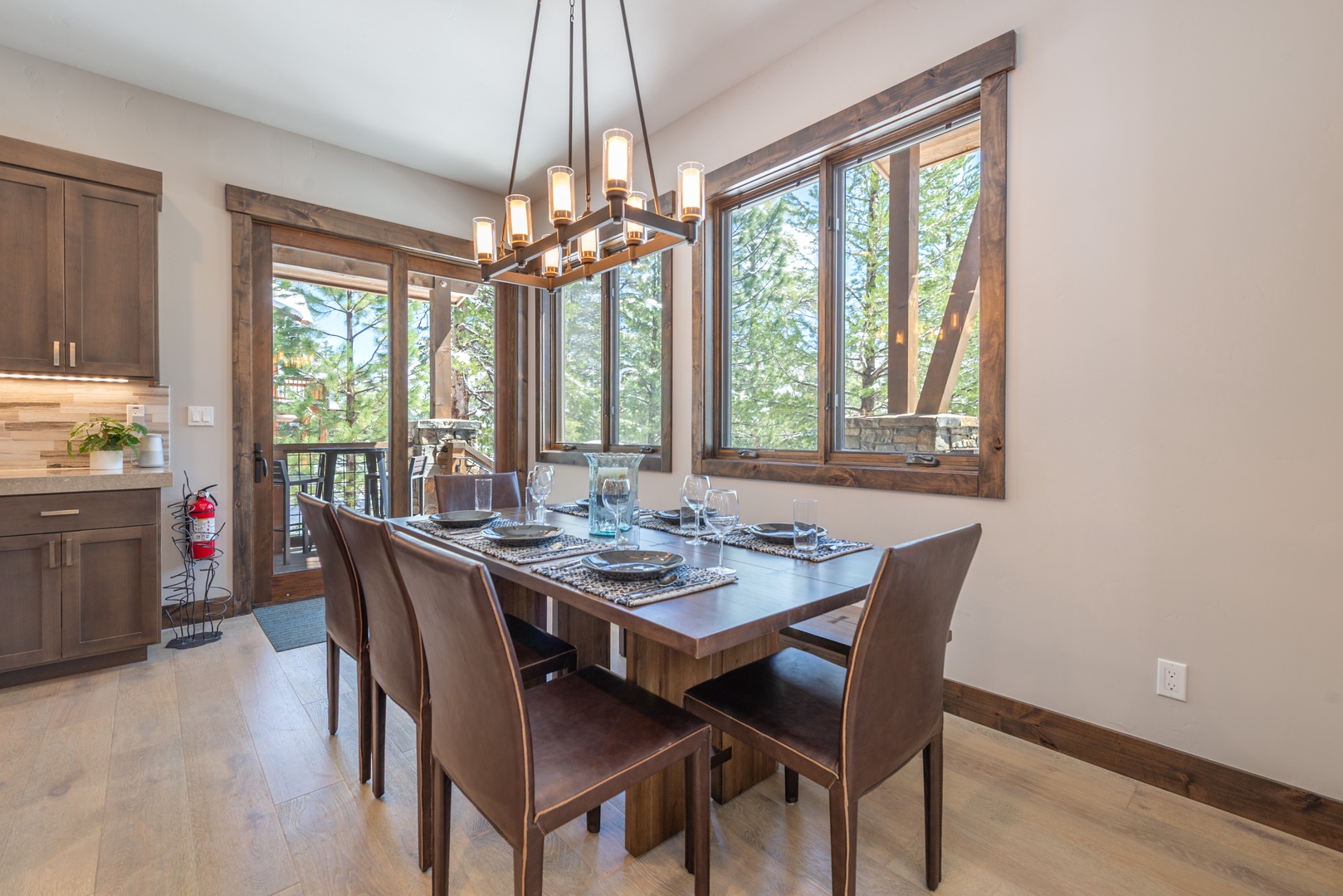 Gather around your elegant dining table where warm wood tones and forest views create the perfect setting for memorable meals together.